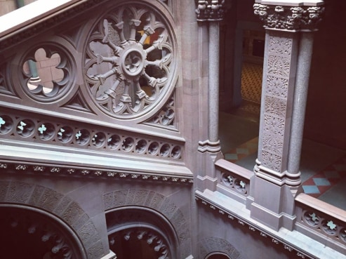 Ornate interior of the Liberty Mutual headquarters features intricate stone carvings and decorative arches. The architectural details include a circular floral pattern and columns with elaborate designs, showcasing classic craftsmanship and design elegance.