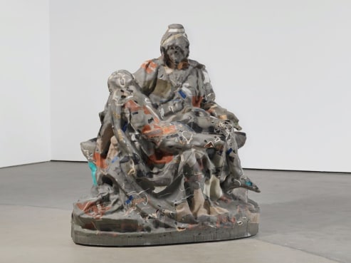 In a minimalist gallery at 1601 Wewatta Street, a distorted, abstract sculpture resembling Michelangelos Pieta captivates viewers with its fragmented and multicolored textures amidst the light gray floor and white walls.