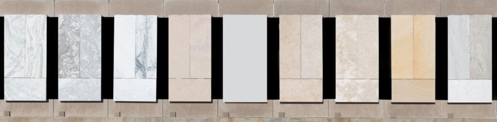 A row of vertical stone and marble panels in various shades and textures, mounted on a wall with black spaces between each panel, creates architectural surfaces that make a lasting impact.