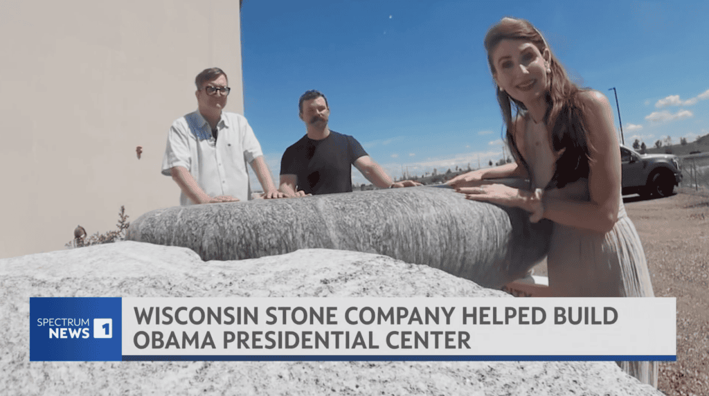 Three people stand outdoors by large stone slabs. A woman in the foreground smiles at the camera, while two men stand behind her. Text reads: “Wisconsin stone company helped build Obama Presidential Center.”.