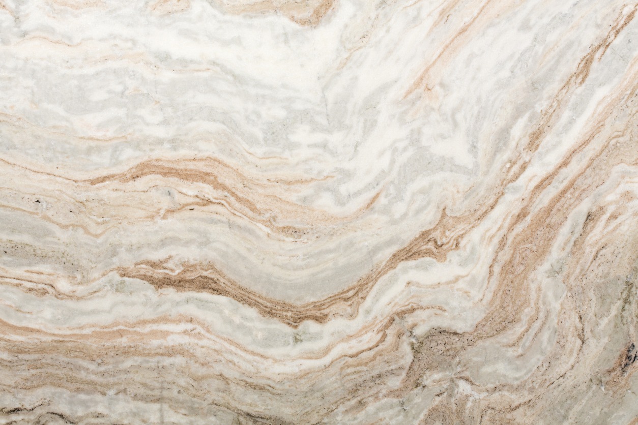 Beige and white marble surface with swirling brown and gray veins, creating a natural wavy pattern across the stone.