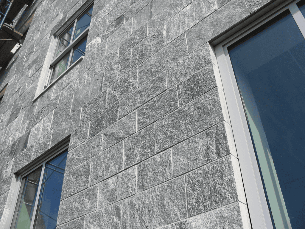 Columns with ornate, intricate carvings and arches in a historic building, illuminated by soft, natural light. The detailed patterns feature floral and geometric designs, highlighting the craftsmanship of the architectural structure.